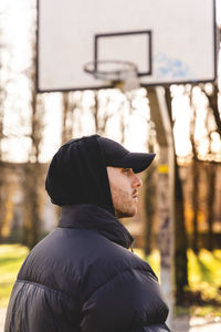 Young man wearing cap standing in park during winter