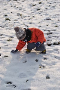 Boy playing on snow covered land during winter