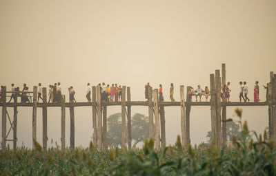 Group of people on fence against clear sky