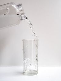 Close-up of drink pouring over glass against white background