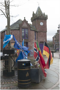 Multi colored flags on street by building against sky