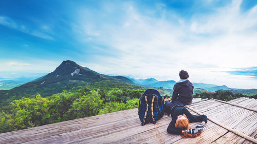 Rear view of man walking on mountain against sky