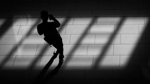 High angle view of silhouette man walking on tiled floor