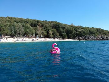 Person in sea against clear blue sky