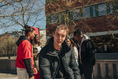 Portrait of young man with friends in background on sunny day