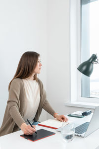 Female sitting at the table with laptop and looking away. woman thinking about the problem at work.