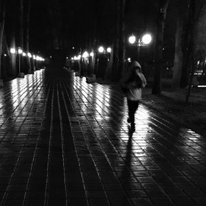 Man walking on illuminated street at night