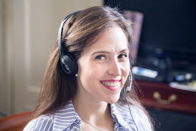 Portrait of smiling female customer service representative answering calls in office