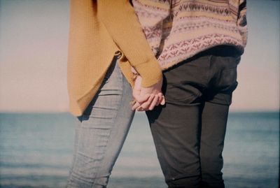 Midsection of couple standing by sea