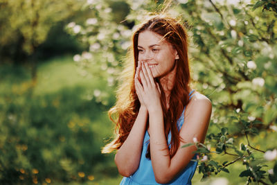 Portrait of young woman standing against plants