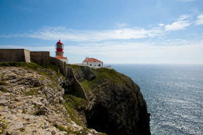 Lighthouse by sea against sky