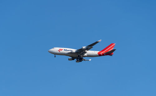 Low angle view of airplane against clear blue sky