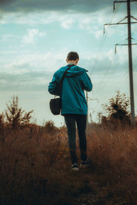Rear view of man standing on field against sky