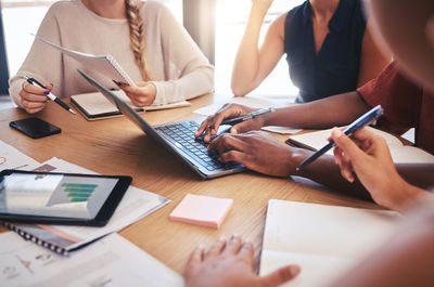 Midsection of business colleagues working on table