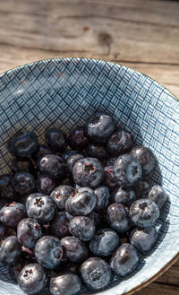 Organic blueberries in a blue and white bowl on the rustic wood background of an old farm table 