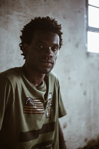 Young man standing against wall of abandoned building