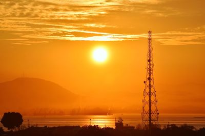 Silhouette electricity pylon against sky during sunset