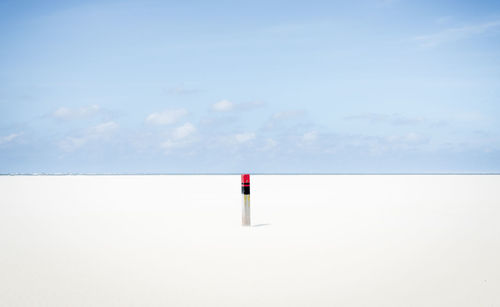 Wooden post at beach against sky