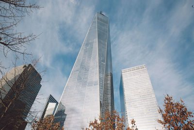 Low angle view of one world trade center by modern buildings in city against sky