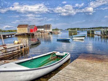 Boats moored in sea by houses against sky