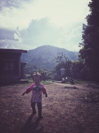 Full length of girl standing on field against sky