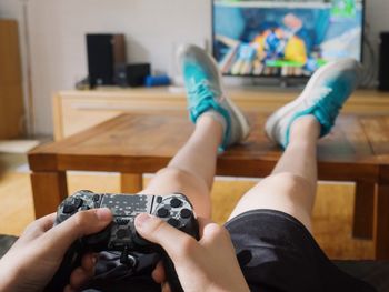 Low section of boy playing video game at home