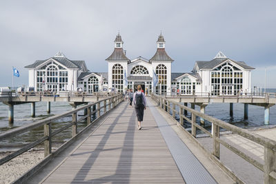 Man walking by building against sky