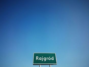 Low angle view of information sign against clear blue sky