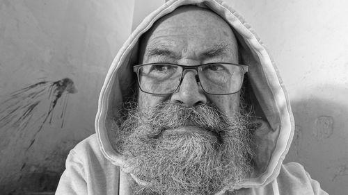 Close-up of senior man with beard against wall