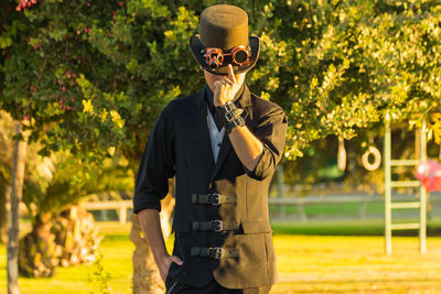 Man in hat standing against trees