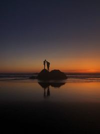 Silhouette horse on beach against sky during sunset