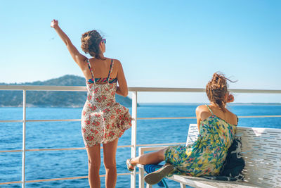 Young women spending leisure time on boat deck against sky