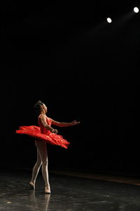 Full length of woman dancing against black background