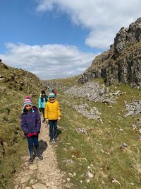 Rear view of people walking on mountain against sky