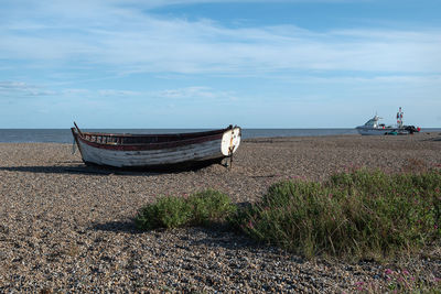 Boat moored on beach against sky