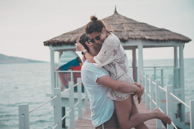 Loving boyfriend carrying girlfriend while standing on pier