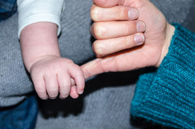 Cropped image of baby holding mother hand