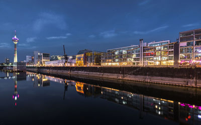 Reflection of illuminated buildings in river against sky