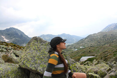 Woman sitting on mountain against sky
