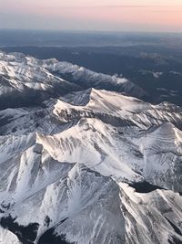 Aerial view of snowcapped mountains against sky during sunset