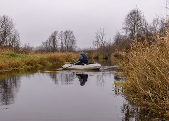 Man in boat on lake against sky