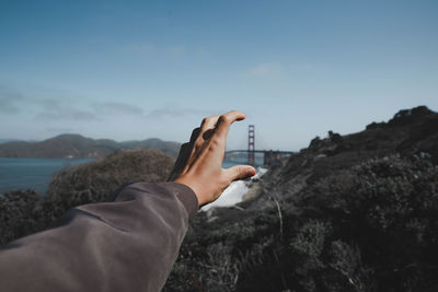 Optical illusion of woman gesturing against bridge