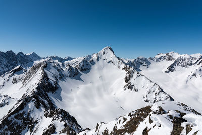 Scenic view of snowcapped mountains against clear blue sky