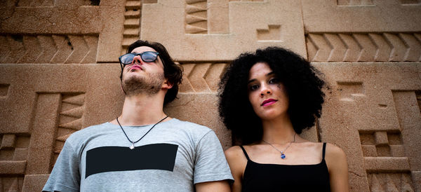 Low angle view of young couple standing against wall