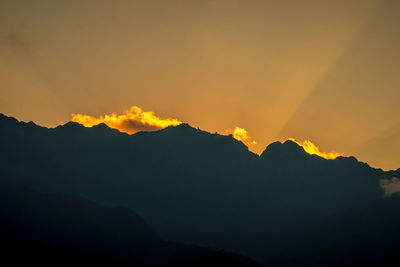 Scenic view of silhouette mountains against orange sky