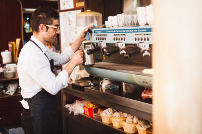 Male owner pouring coffee in cup