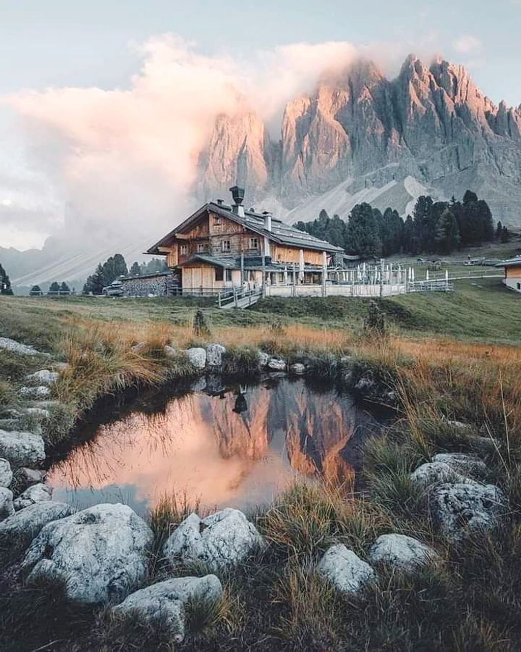 mountain, architecture, landscape, building, built structure, environment, sky, wilderness, nature, building exterior, scenics - nature, cloud, house, water, beauty in nature, land, travel destinations, no people, travel, plant, snow, winter, mountain range, hut, cold temperature, outdoors, rural scene, tourism, residential district, lake, grass, tranquility, non-urban scene, morning, village