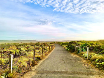 Road amidst field against sky