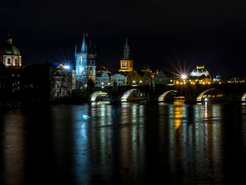 Illuminated bridge over river in city at night