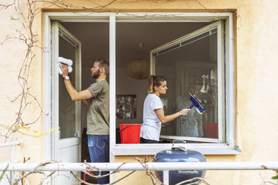 Woman and man cleaning window together